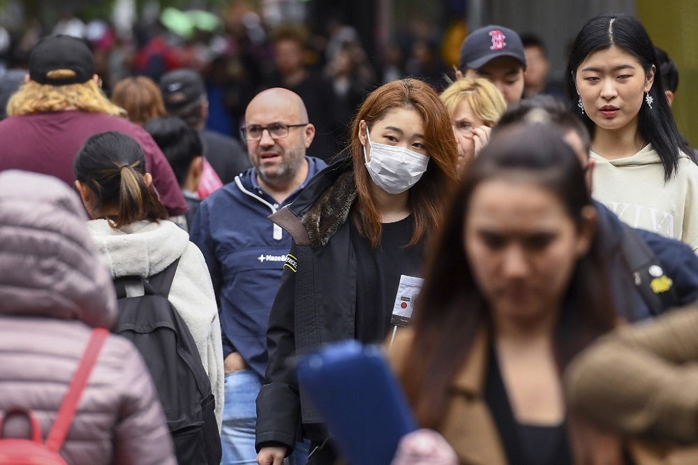 A woman wearing a face mask crosses the street in Melbourne on March 5, 2020. u00e2u20acu201d AFP pic