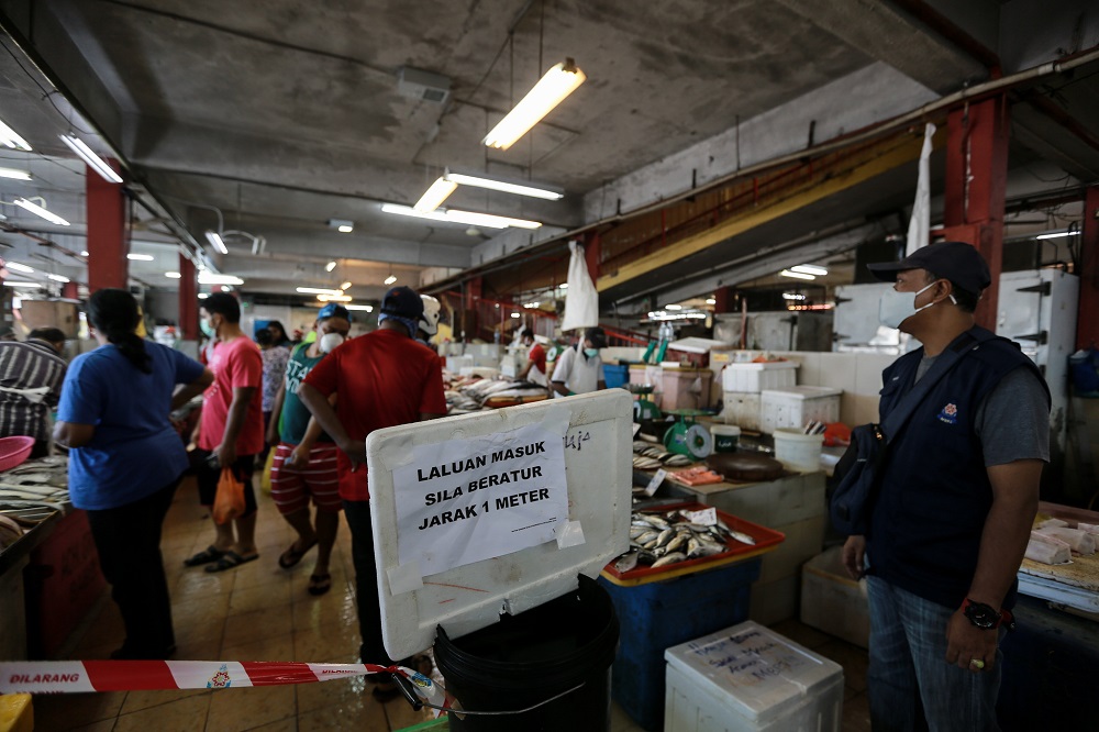 A signboard reminding patrons to practise social distancing is seen at a wet market in Petaling Jaya March 25,2020.  — Picture by Ahmad Zamzahuri