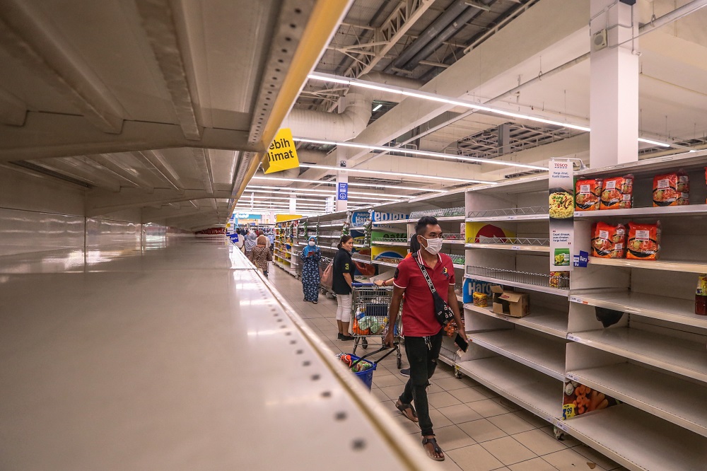 People walk by near empty shelves are seen at Tesco Ampang, amid panic buying following the restriction of movement order announced by the government, in Kuala Lumpur March 17, 2020. u00e2u20acu201d Picture by Firdaus Latif
