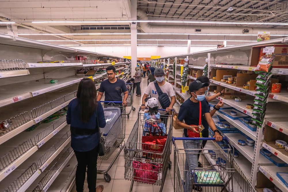 People walk by near empty shelves are seen at Tesco Ampang, amid panic buying following the restriction of movement order announced by the government, in Kuala Lumpur March 17, 2020. — Picture by Firdaus Latif