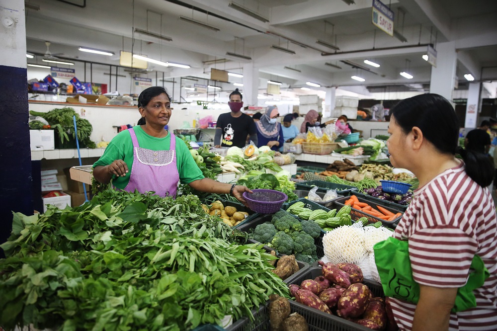 A customer buys vegetables from M. Ratha's (left) stall at the SS15 wet market in Subang Jaya March 18, 2020. — Picture by Yusof Mat Isa