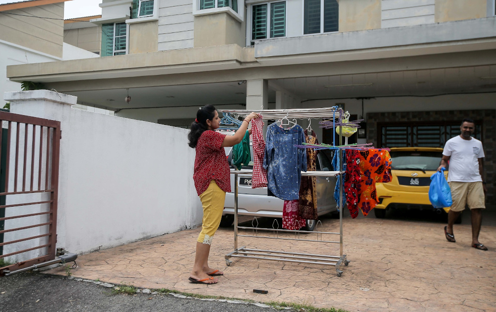 Gouri Sivananthan, 34, a housewife, and her husband Dinesh Kumar Purusoithman, 35, doing chores at their home in Bandar Baru Sri Klebang in Ipoh. — Picture by Farhan Najib