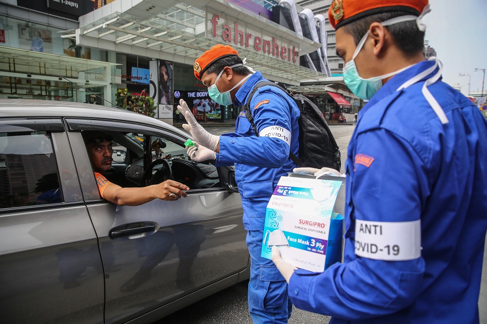 Malaysia Civil Defence Force personnel distributing protective face masks to the public in Kuala Lumpur March 21, 2020. u00e2u20acu201d Picture by Yusof Mat Isa
