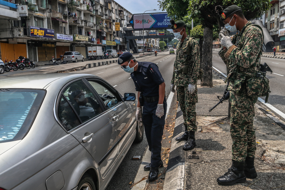 Soldiers and police officers conducting checks at a roadblock on day five of the movement control order (MCO) at Jalan Loke Yew in Kuala Lumpur March 22, 2020. u00e2u20acu201d Picture by Firdaus Latif