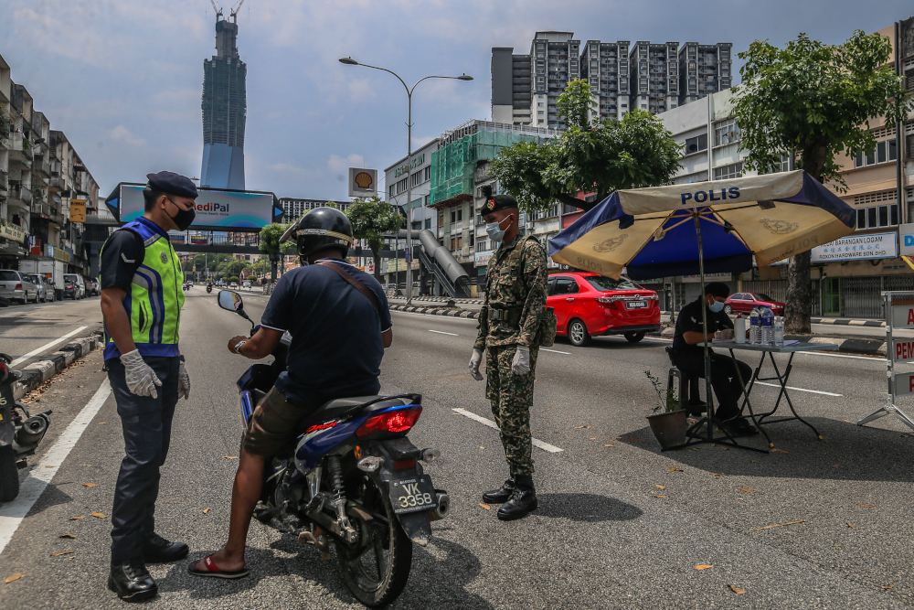 Soldiers and police officers conducting checks at a roadblock on day five of the movement control order (MCO) at Jalan Loke Yew in Kuala Lumpur March 22, 2020. u00e2u20acu201d Picture by Firdaus Latif