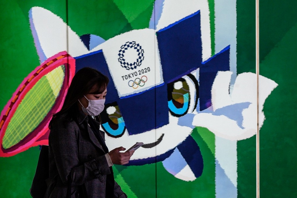 A woman wearing a face mask walks in the tunnel of a metro station with a poster of Miraitowa, official mascot of the Tokyo 2020 Olympics March 11, 2020. u00e2u20acu201d AFP pic