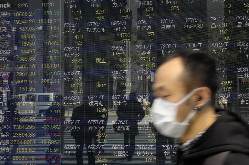 Pedestrians walk in front of a quotation board displaying stock prices on the Tokyo Stock Exchange in Tokyo March 26, 2020. u00e2u20acu201d AFP pic