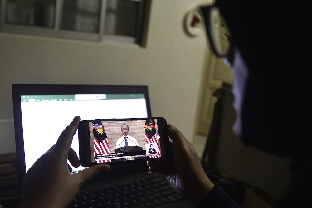 People watch a live broadcast of Prime Minister Tan Sri Muhyiddin Yassinu00e2u20acu2122s special Covid-19 address to the nation. u00e2u20acu201d Picture by Miera Zulyana 