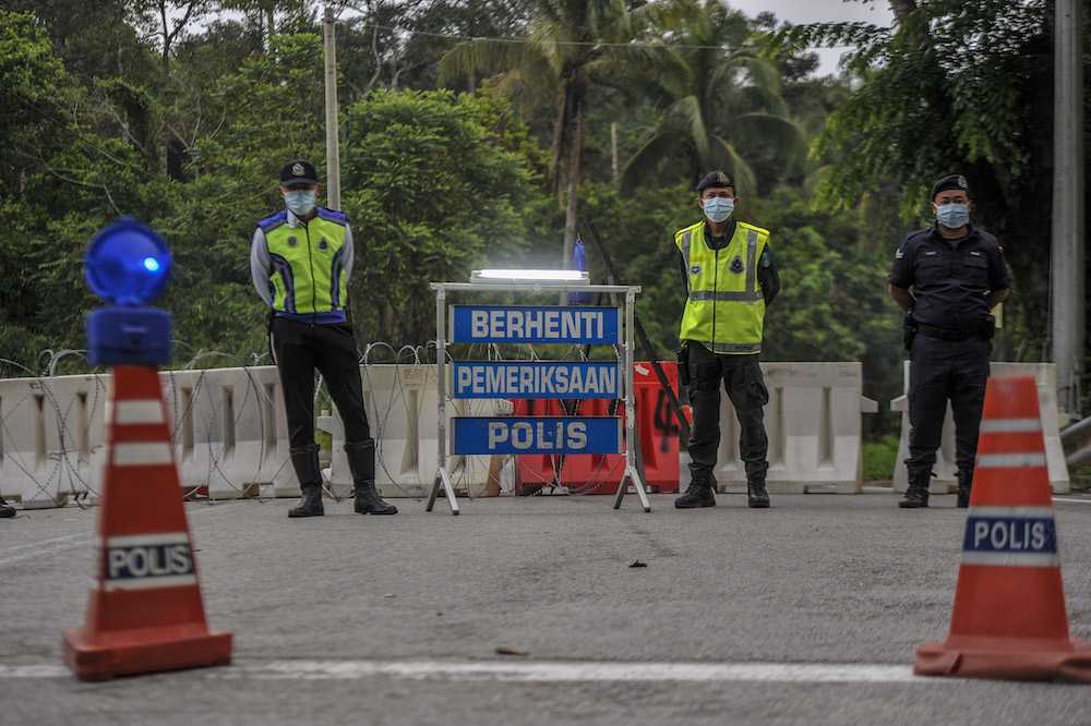 Police officers conducting checks at a roadblock during the enhanced movement control order (EMCO) in seven villages in Hulu Langat, March 30, 2020. u00e2u20acu201d Picture by Shafwan Zaidon