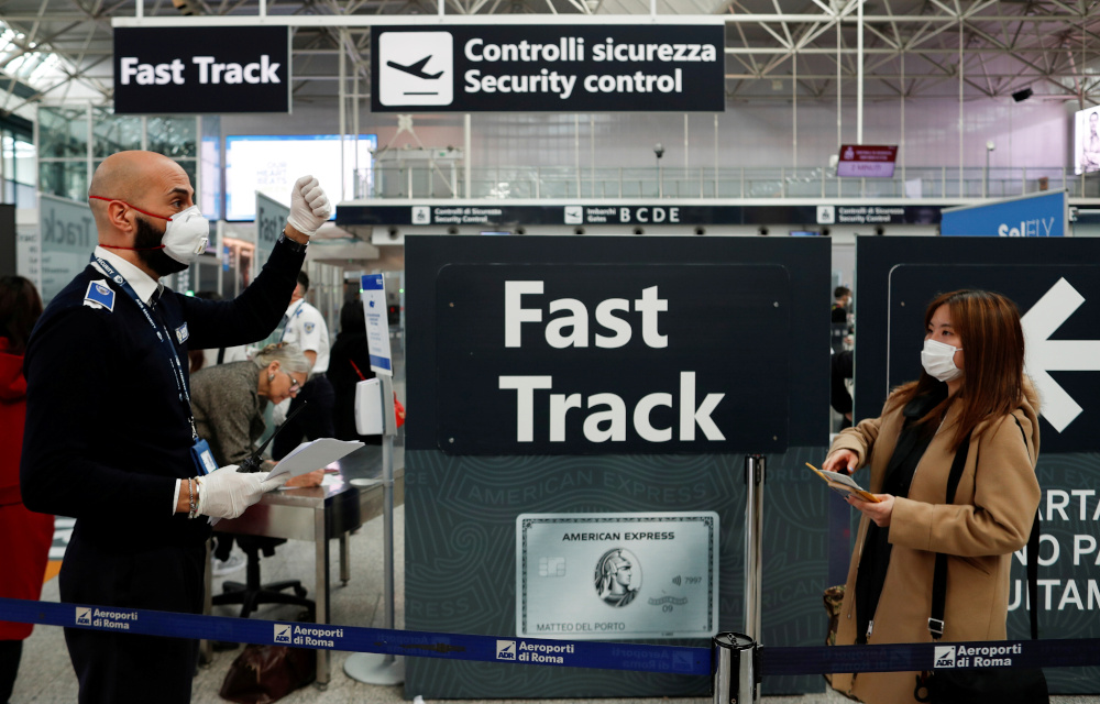 A passenger and airport staff member wearing protective face masks are seen at Romeu00e2u20acu2122s Fiumicino airport, on the third day of an unprecedented lockdown across of all Italy imposed to slow the outbreak of coronavirus, in Rome, Italy, March 12, 2020. u00e2u20acu201d R