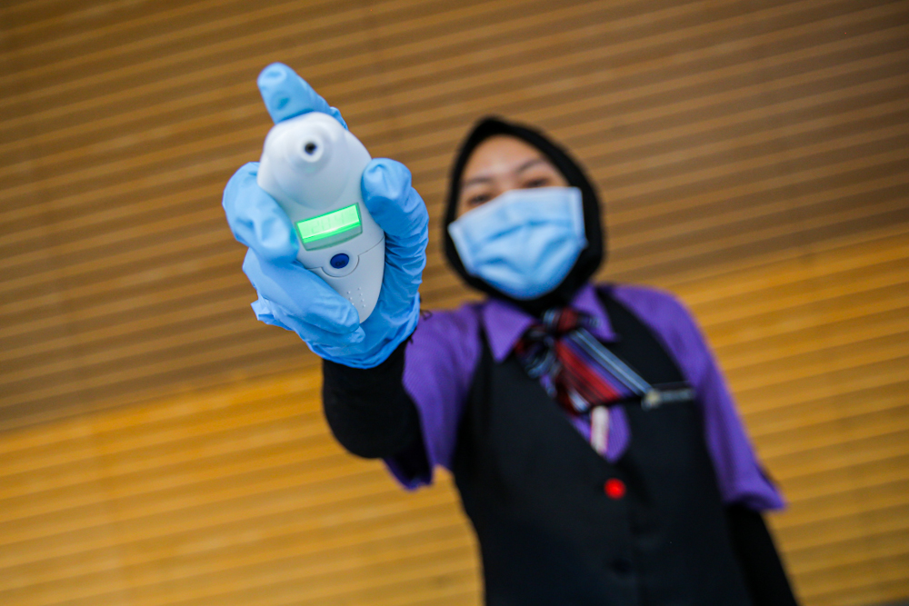 A McDonaldu00e2u20acu2122s worker at the Jalan Tun Perak outlet holds a thermometer to check the temperature of customers March 21, 2020. u00e2u20acu201d Picture by Hari Anggara