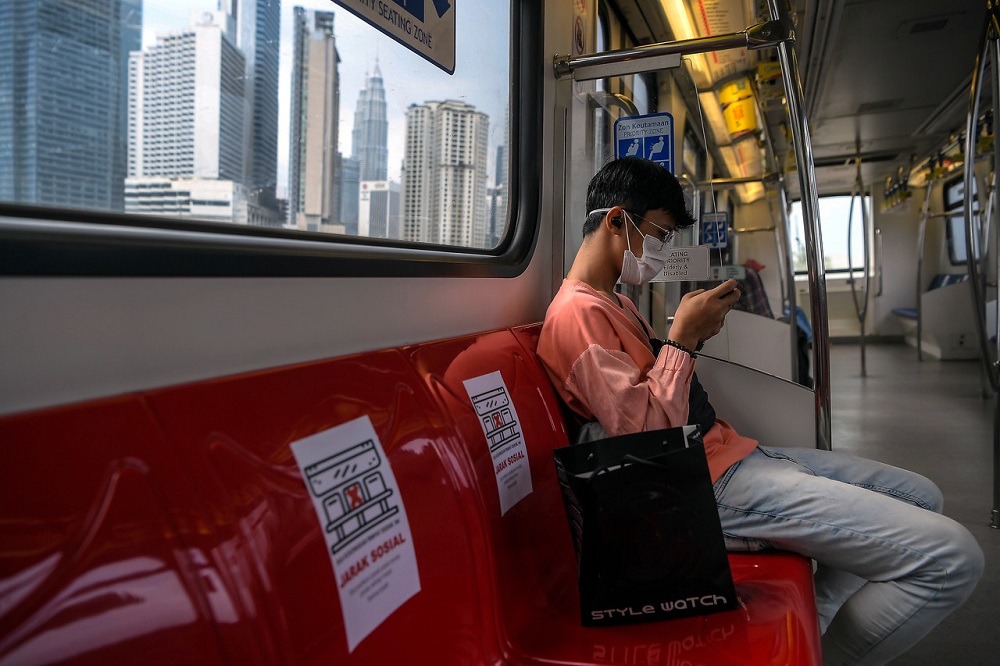 A man uses his mobile phone during a ride on an LRT in Kuala Lumpur March 24, 2020. Authorities have stressed the importance of social distancing as seen on posters attached to the seats here in a move to prevent the spread of the Covid-19 virus. u00e2u20acu201d Bern