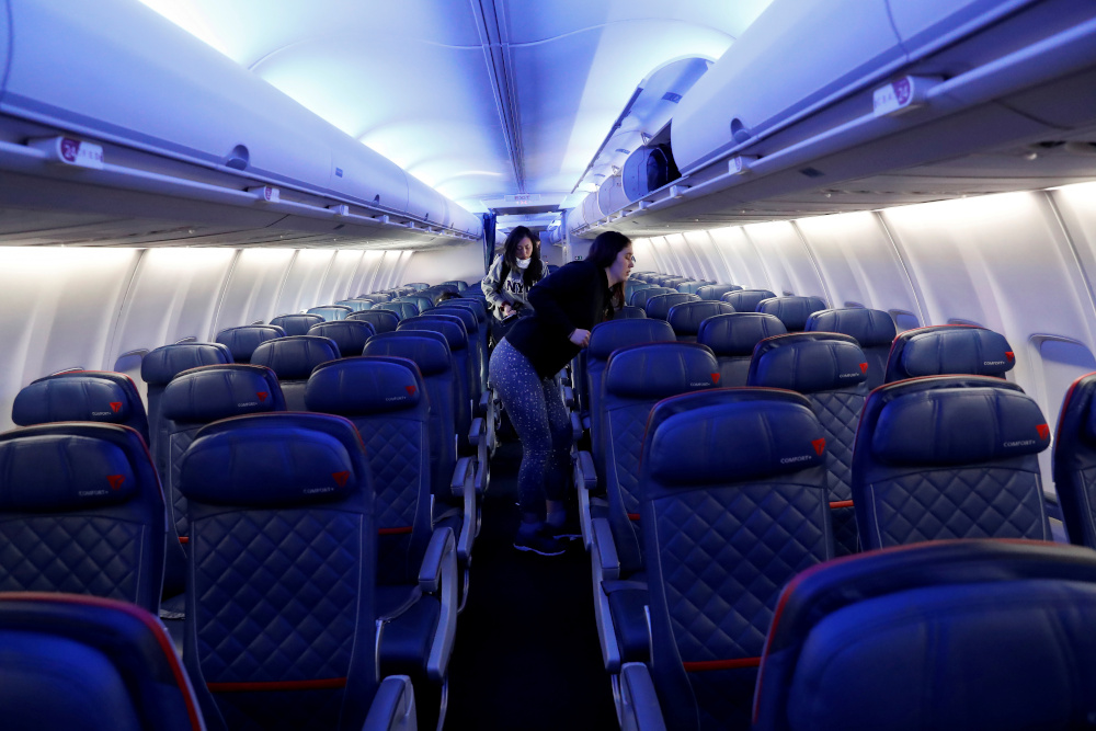 Air travellers grab carry-on luggage behind rows of empty seats aboard a Delta flight, as coronavirus disease disruption continues across the global industry March 17, 2020. u00e2u20acu201d 