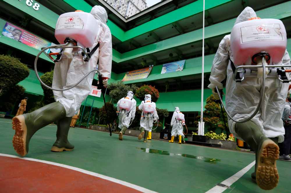 Volunteers from Indonesia's Red Cross prepare to spray disinfectant at a school closed amid the spread of coronavirus in Jakarta. u00e2u20acu2022 Reuters pic