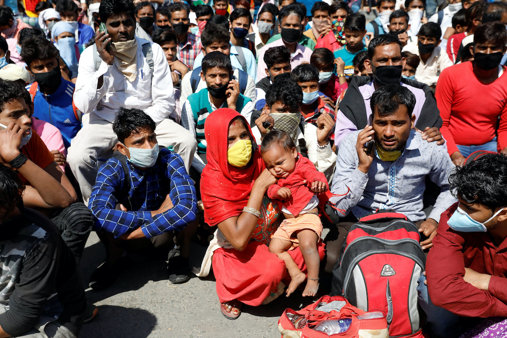 Migrant workers wait for buses along a highway with their families as they return to their villages, during a 21-day nationwide lockdown to limit the spreading of coronavirus disease (Covid-19), in Ghaziabad, on the outskirts of New Delhi, India March 28,