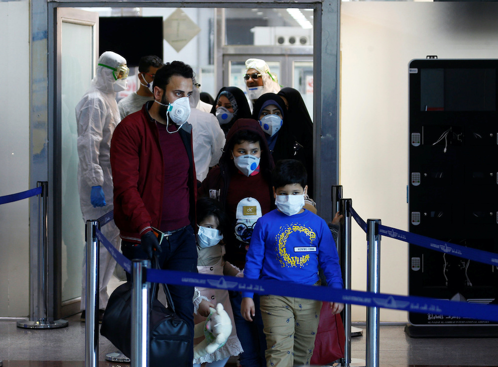 Passengers wearing protective face masks arrive from Iran, following an outbreak of the coronavirus, at Najaf airport, in the holy city of Najaf, Iraq February 26, 2020. Picture taken February 26, 2020. u00e2u20acu201d Reutersnn