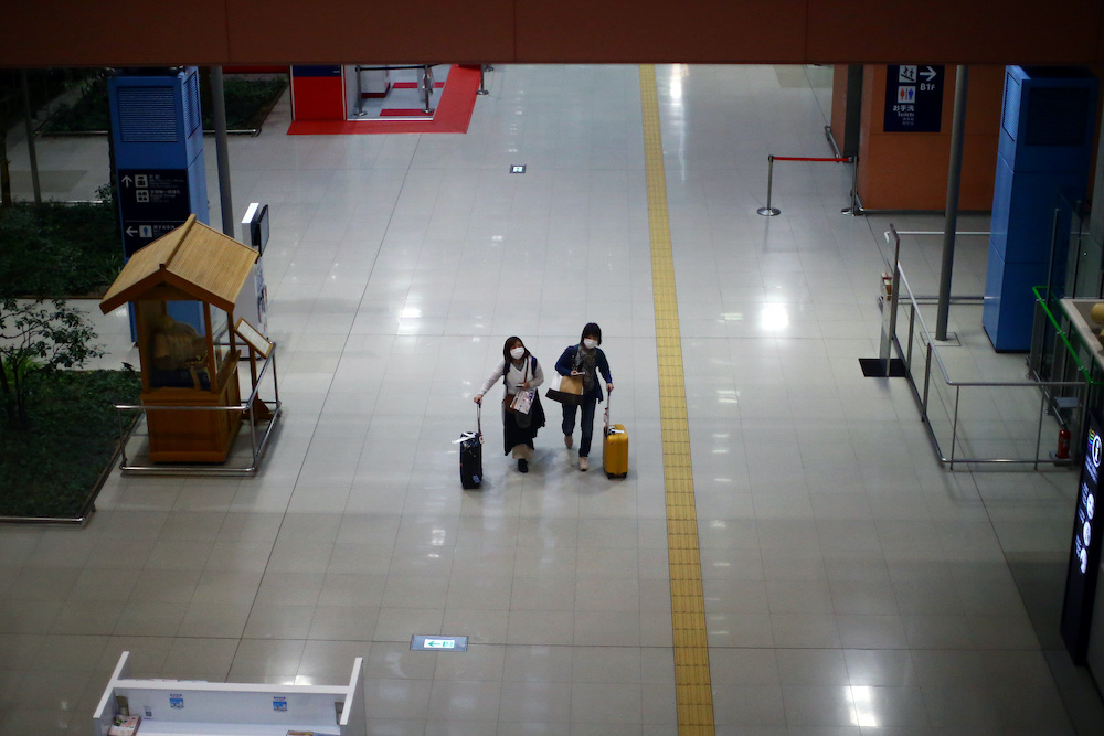 Passengers, wearing protective masks following an outbreak of the coronavirus disease (COVID-19), walk at the almost empty Kansai International Airport in Osaka, Japan, March 14, 2020. u00e2u20acu201d Reuters picnn