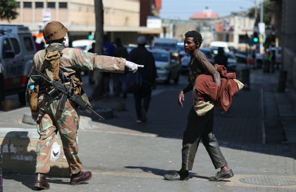A member of the South African National Defence Forces gestures to a homeless men during their patrols on the first day of a nationwide lockdown for 21 days to try to contain the coronavirus disease (Covid-19) outbreak, in Johannesburg, South Africa, March