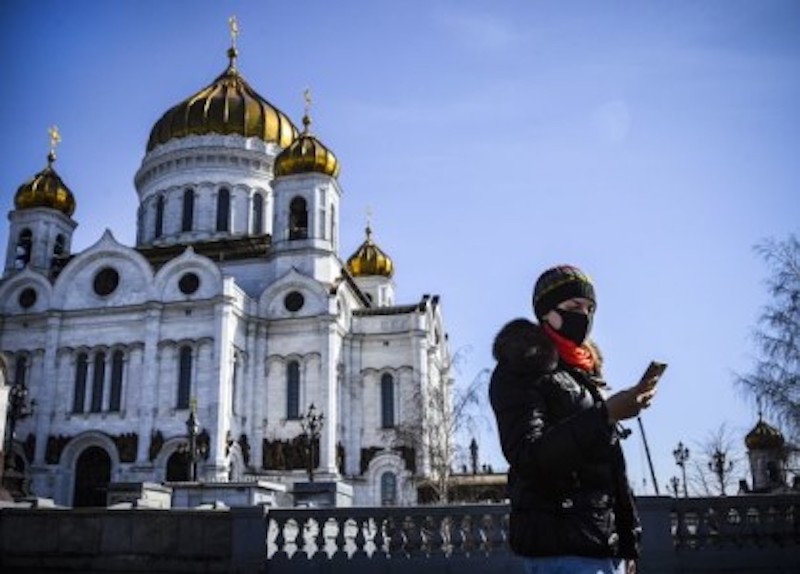 A woman uses her phone outside the Cathedral of Christ the Saviour in downtown Moscow on March 26, 2020. u00e2u20acu201d AFP-Relaxnews pic