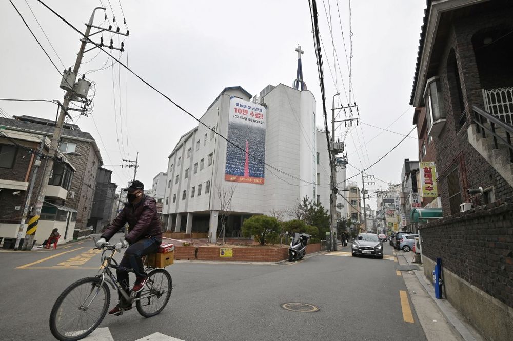 A man wearing a face mask rides a bicycle in front of a branch of the Shincheonji Church of Jesus, which is temporarily closed by the government to help prevent the spread of the COVID-19 coronavirus, in Seoul on March 1, 2020. u00e2u20acu201d AFP pic