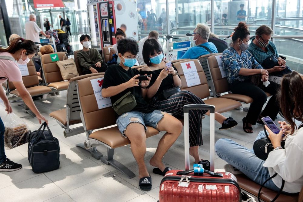 People wearing face masks sit on seats with signs telling travellers where they may sit, in order to observe social distancing rules amid concerns over the coronavirus, at Suvarnabhumi Airport in Bangkok, March 25, 2020. u00e2u20acu201d AFP pic