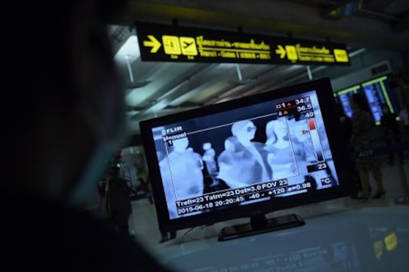An Airports of Thailand employee (left) monitors a screen as travellers walk past a thermoscan checking their body temperature on arrival at Bangkoku00e2u20acu2122s Suvarnabhumi Airport. u00e2u20acu201d AFP-Relaxnews pic
