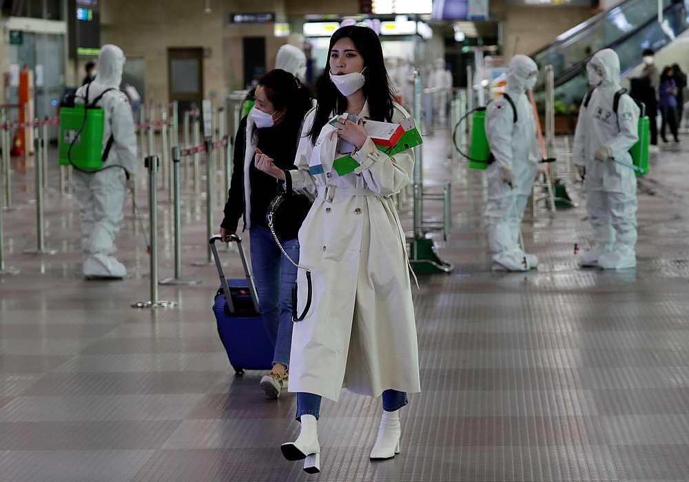 Travellers walk past South Korean soldiers mobilised for disinfection work at the international airport  in Daegu March 6, 2020. u00e2u20acu201d Reuters pic