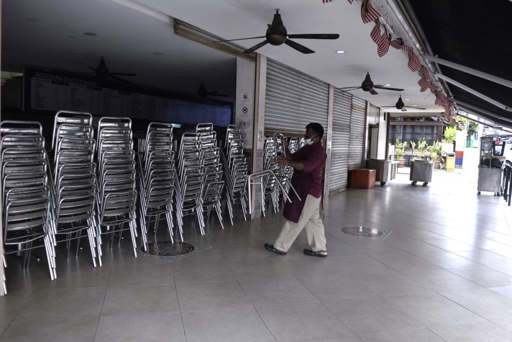 Staff at Devi's Corner are seen stacking up chairs as the movement control order kicks in on March 18, 2020. u00e2u20acu201d Picture by Miera Zulyana
