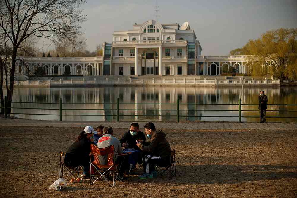 People wearing protective masks play cards in a park on a sunny day in Beijing as China is recovering from a Covid-19 outbreak March 21, 2020. u00e2u20acu201d Reuters pic