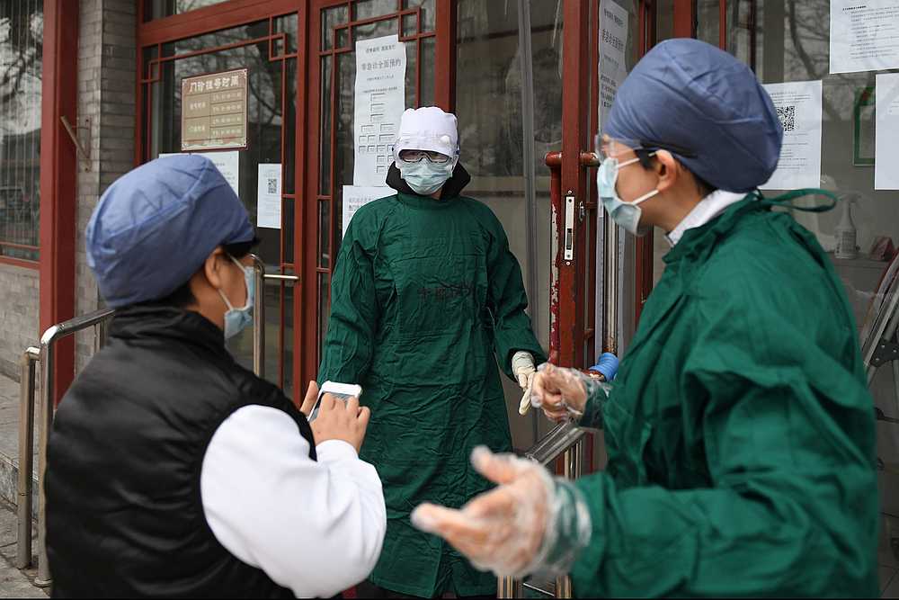 Medical staff wear facemasks to protect against the Covid-19 coronavirus as they chat outside a hospital in Beijing. u00e2u20acu201d AFP pic