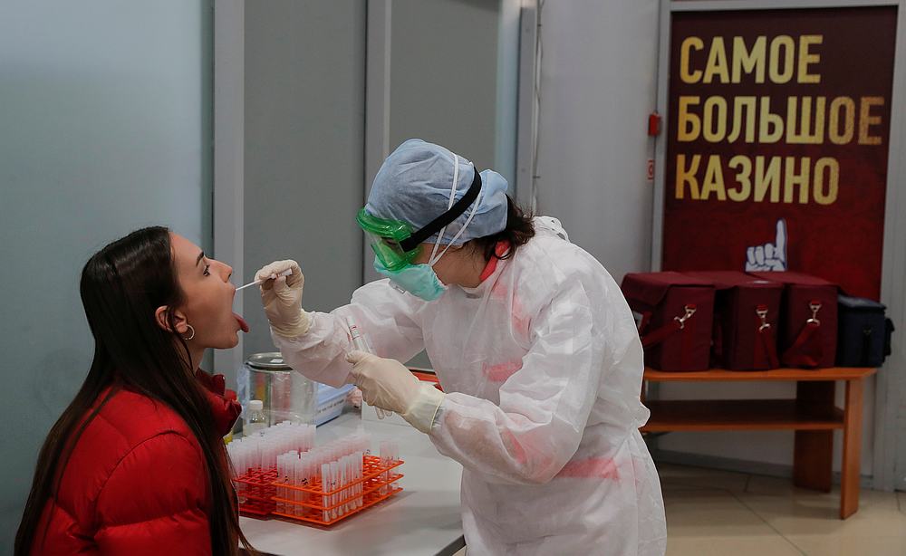 A nurse wearing protective gear takes a swab from a passenger at the Minsk National Airport, Belarus March 19, 2020. The sign reads 'The biggest casino' u00e2u20acu201d Reuters pic