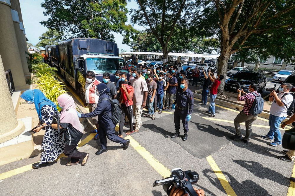 Police escort detainees who flouted the movement control order at the Butterworth Court Complex in Penang March 31, 2020. u00e2u20acu201d Picture by Sayuti Zainudin
