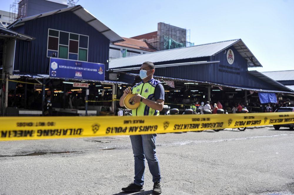 Police cordon off the Chow Kit Market with yellow tape as workers disinfect the premises March 25, 2020. u00e2u20acu201d Picture by Shafwan Zaidon