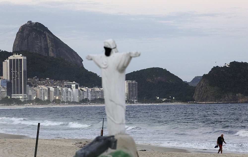 A man walks as a Christ the Redeemer statue made from sand is pictured with protective mask in Copacabana beach, Rio de Janeiro, Brazil March 28, 2020. u00e2u20acu201d Reuters pic