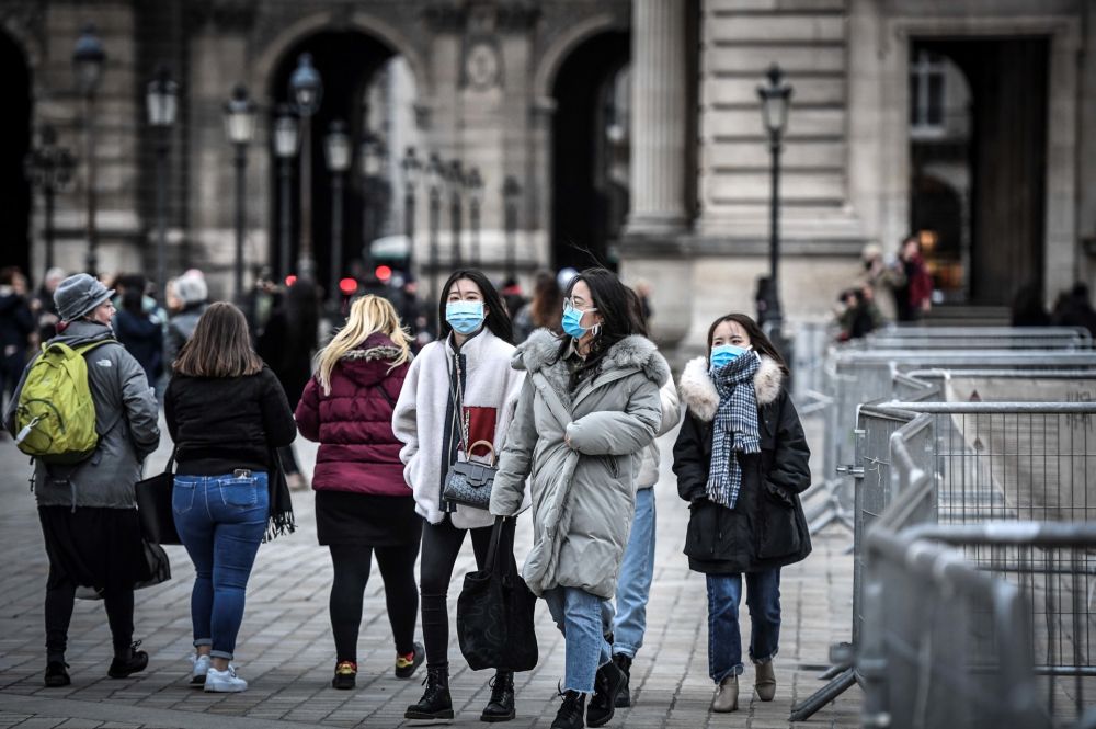Tourists wearing a protective face mask amid fears of the spread of the Covid-19 novel coronavirus walk at the Pyramide du louvre area on February 28, 2020 in Paris. u00e2u20acu201d AFP pic