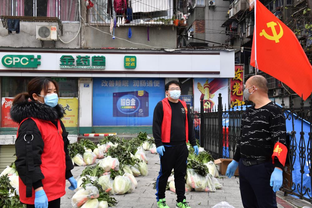 Volunteers wearing face masks stand next to vegetables to be delivered to residents of a residential area in Wuhan, Hubei province, China March 5, 2020. u00e2u20acu201d China Out pic via Reuters