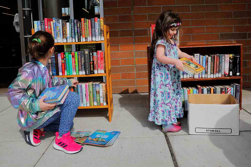 Sisters Ava and Sadie Williams choose books while picking up lunch with their mother at the Olympic Hills Elementary School, after schools were closed in Seattle, Washington March 17, 2020. u00e2u20acu201d Reuters pic 