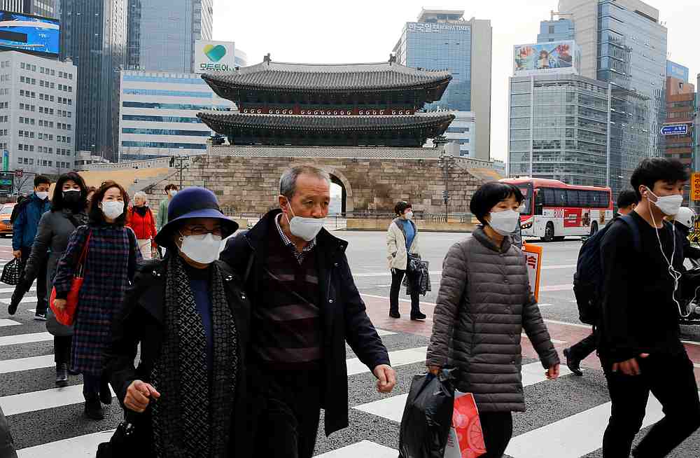 People wearing masks to prevent contracting Covid-19 cross a street in downtown Seoul, South Korea March 9, 2020. u00e2u20acu201d Reuters pic 