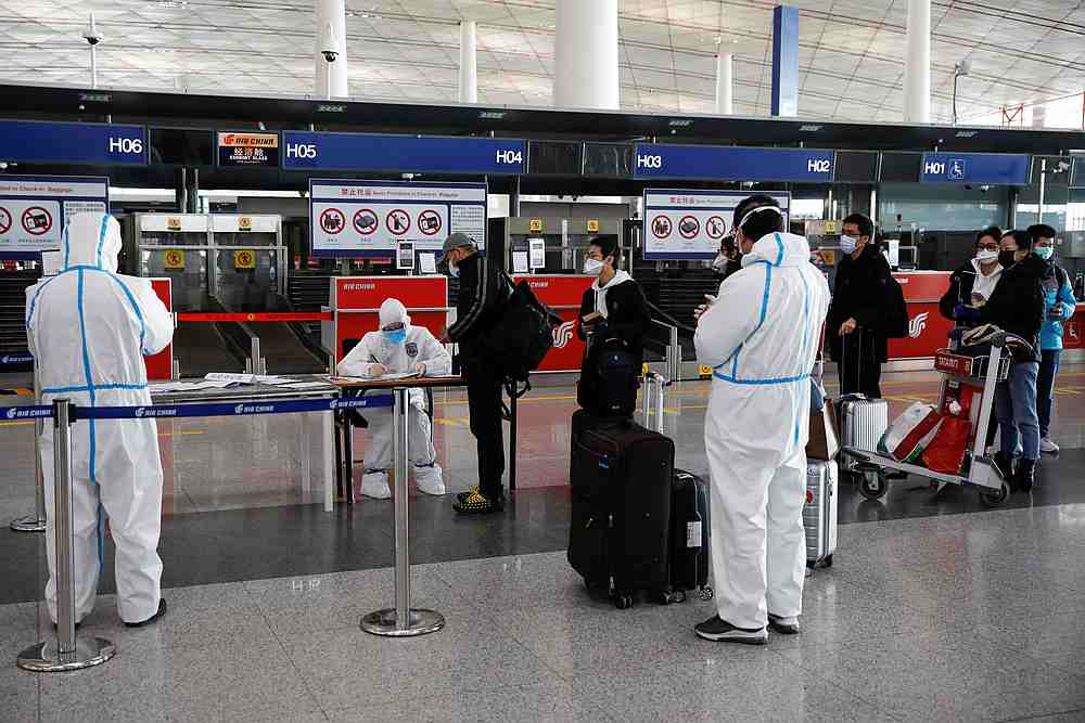 Staff members wearing protective suits register passengers in front of a check-in counter of Air China at Beijing Capital International Airport, China March 16, 2020. u00e2u20acu201d Reuters pic
