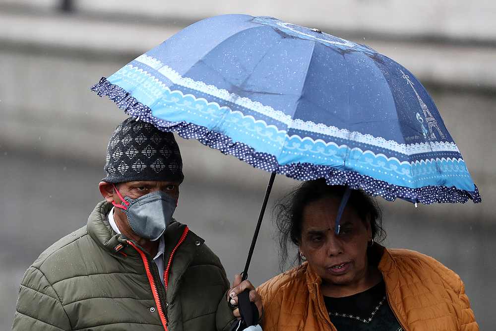 A man wearing a protective mask takes shelter under an umbrella as he walks along the Southbank in London, Britain March 5, 2020. u00e2u20acu201d Reuters pic 