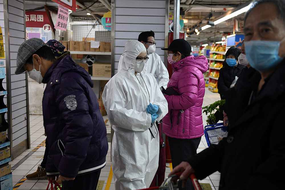 Workers wear protective clothing as a preventive measure against Covid-19 as they monitor customers to make sure they stand one metre apart as they queue in a supermarket in Beijing. u00e2u20acu201d AFP pic
