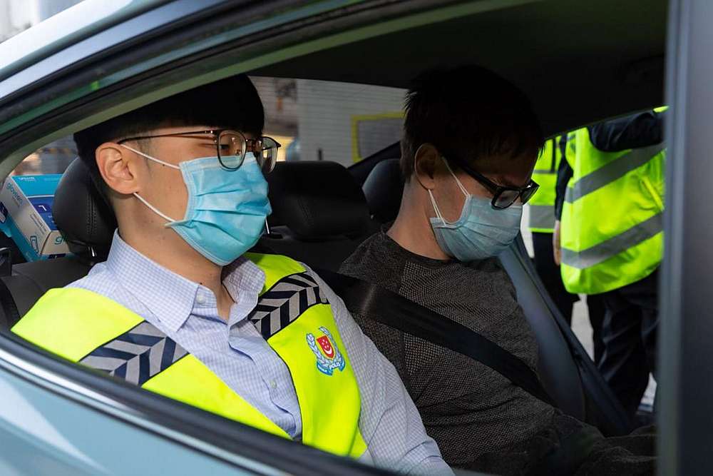 Canadian David James Roach (centre) as he arrives in Singapore to face charges of robbery and money laundering March 17, 2020. u00e2u20acu201d Singapore Police handout via AFP