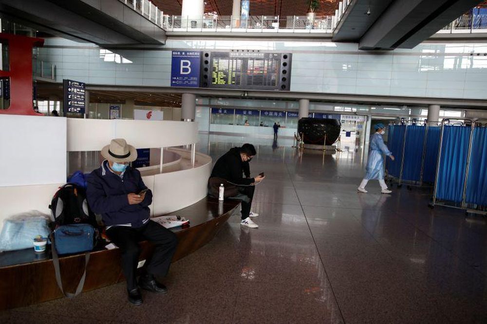 People wearing face masks look at their cellphones at Beijing Capital International Airport, in Beijing, China, March 16, 2020. u00e2u20acu201d Reuters pic
