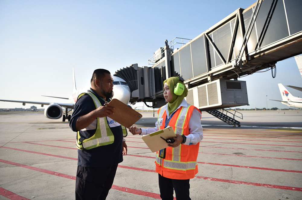 Nur Syamimi (right) liaising with a colleague on the tarmac. — Picture courtesy of Malaysia Airlines