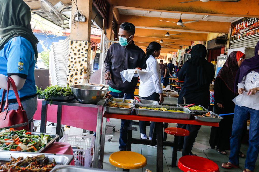 Customers pack food to go at a food court in Penang March 18, 2020. u00e2u20acu201d Picture by Sayuti Zainudin