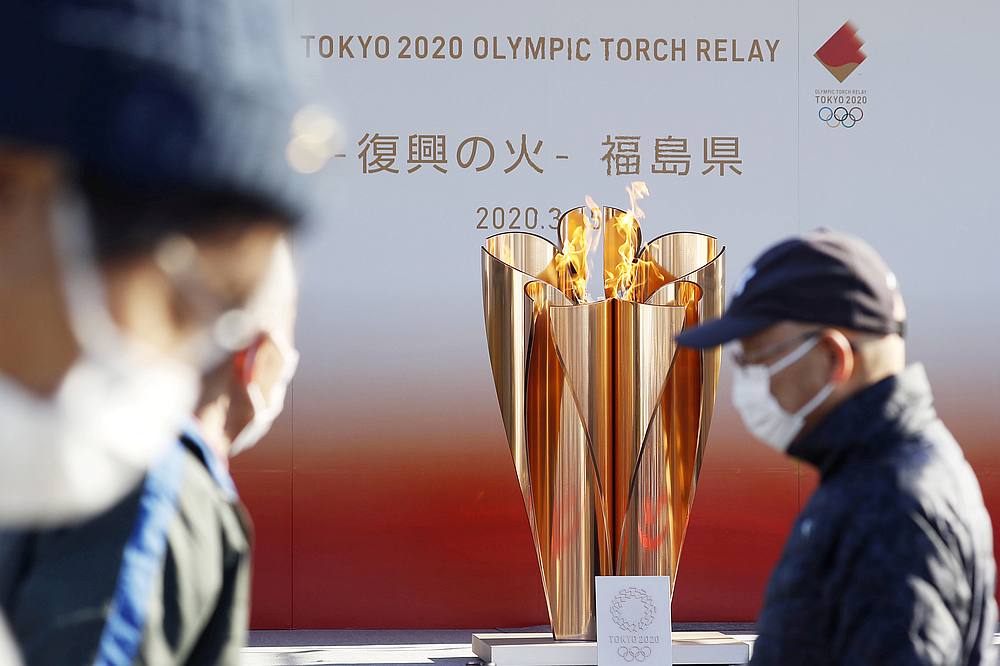 Olympic cauldron is seen behind visitors wearing protective masks amid the spreading Covid-19 outbreak in Iwaki, Fukushima prefecture, Japan March 25, 2020. u00e2u20acu201d Kyodo pic via Reuters