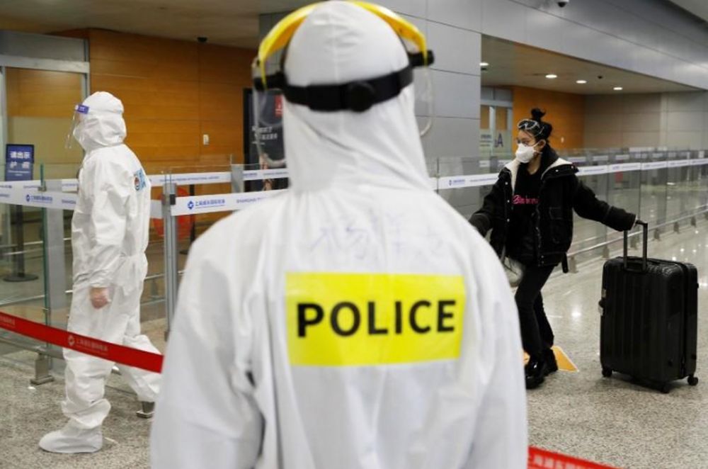 A police officer in a protective suit keeps watch on inbound travellers at Shanghai Pudong International Airport following a global outbreak of coronavirus disease, in Shanghai, China March 20, 2020. u00e2u20acu201d cnsphoto via Reuters