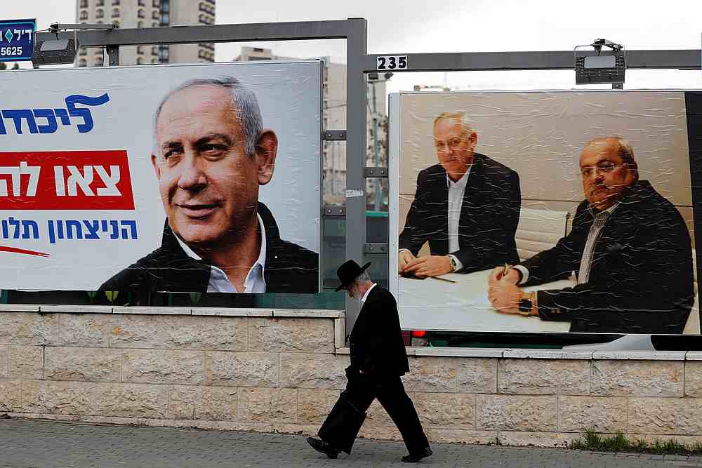 A Jewish man walks Israeli campaign banners, depicting (from left) Benjamin Netanyahu, Benny Gantz and Ahmad Tibi in Jerusalem February 20, 2020. u00e2u20acu201d Reuters pic