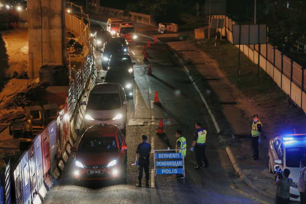 Police officers inspect a vehicle during a roadblock in Kepong March 19, 2020. u00e2u20acu2022 Picture by Ahmad Zamzahuri