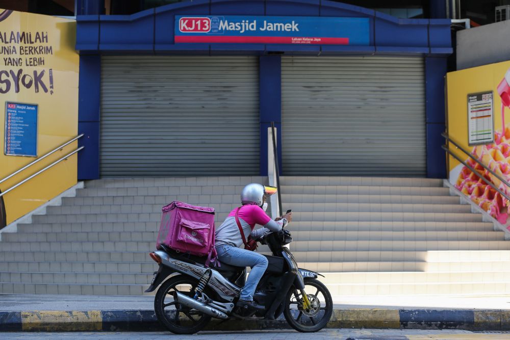 A Foodpanda rider idles in front of the Masjid Jamek LRT station in Kuala Lumpur on day eight of the movement control order March 25, 2020. — Picture by Yusof Mat Isa